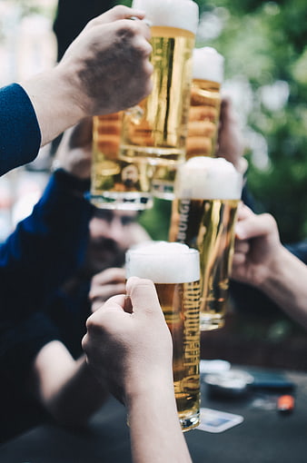 Friends clinking beer glasses in a toast outdoors