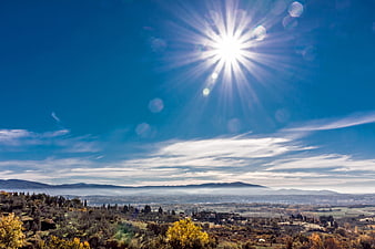 Sunburst over Tuscany landscape with autumn trees and mountains