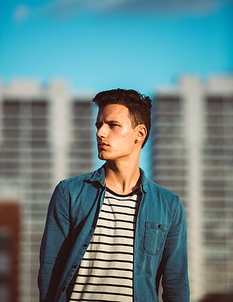 Young man in denim jacket on urban rooftop