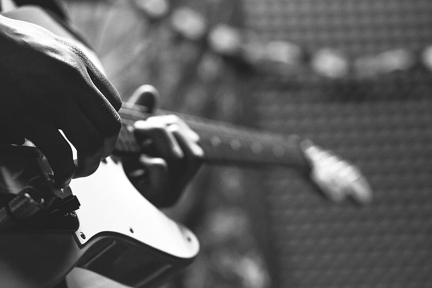 Close-up of hands playing electric guitar in black and white