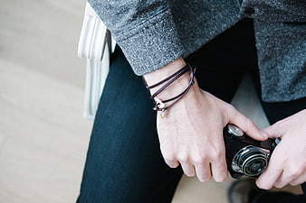 Close-up of hands holding vintage camera with leather bracelet
