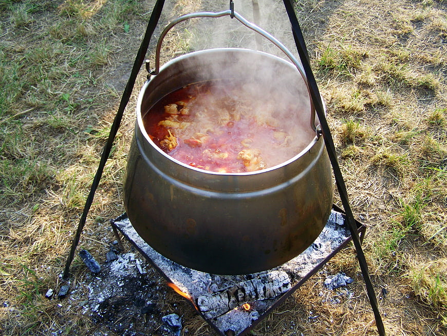 Traditional Goulash Simmering In Metal Cauldron Over Open Campfire