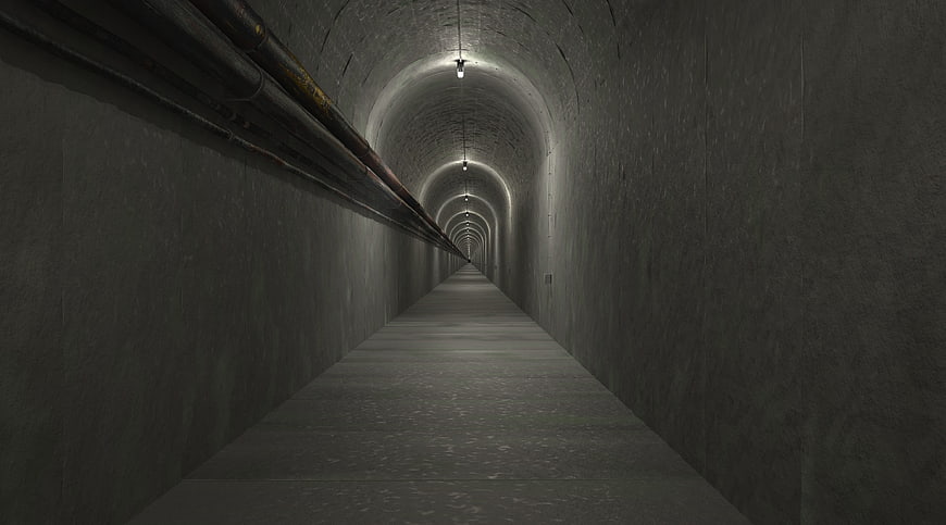 Dark concrete tunnel with pipes and overhead lights