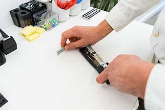Hands Loading Staples into Office Stapler on White Desk