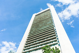 Low angle view of modern white skyscraper against blue sky