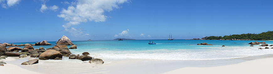 Panoramic tropical beach with turquoise water and granite boulders