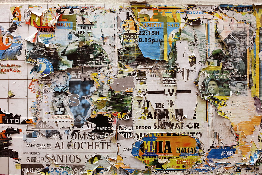 Textured wall covered in torn posters and flyers