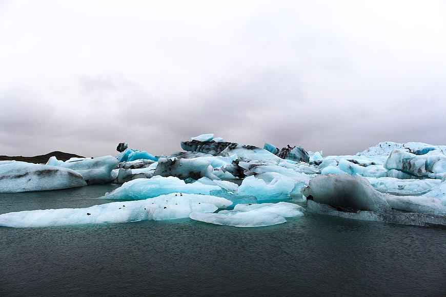 Blue Icebergs Floating in Glacial Lagoon Under Overcast Sky