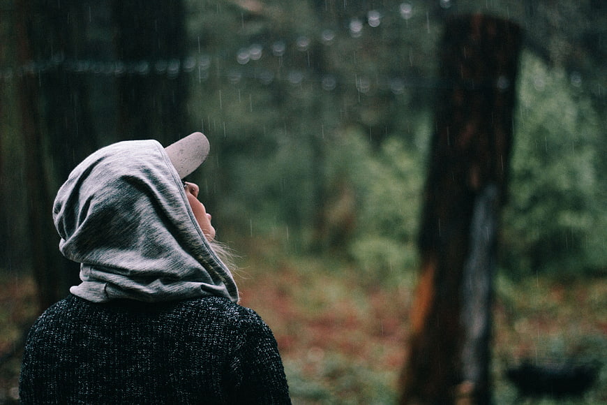 Woman in Hoodie Looking Up in Rainy Forest