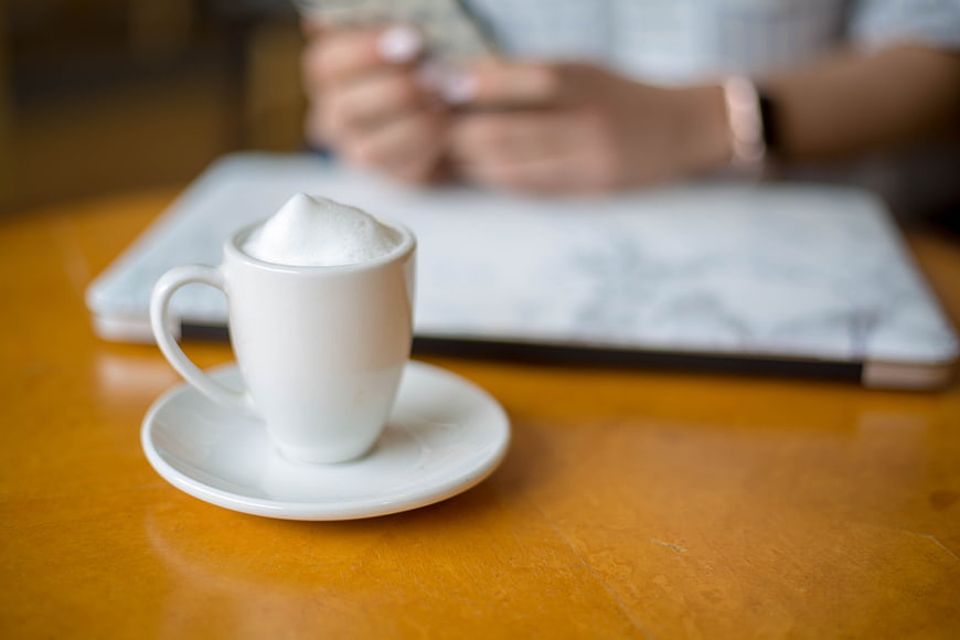 White coffee cup on wooden table with laptop background