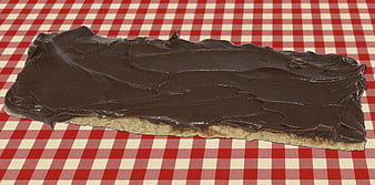 Chocolate spread on bread slice on red checkered tablecloth