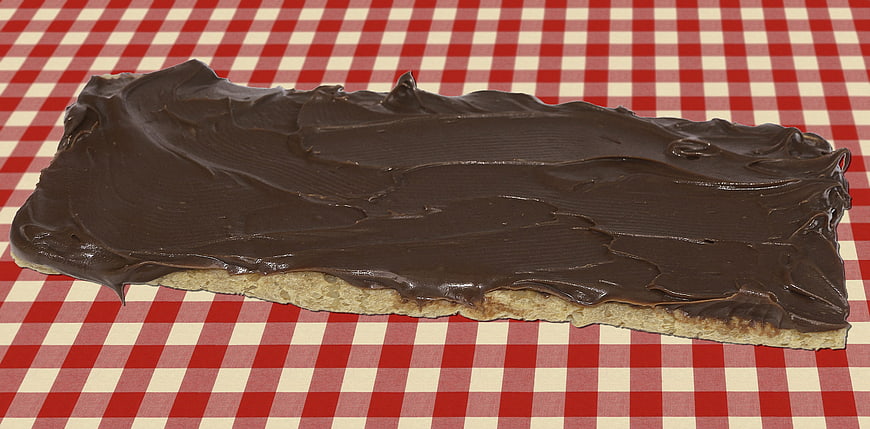 Chocolate spread on bread slice on red checkered tablecloth