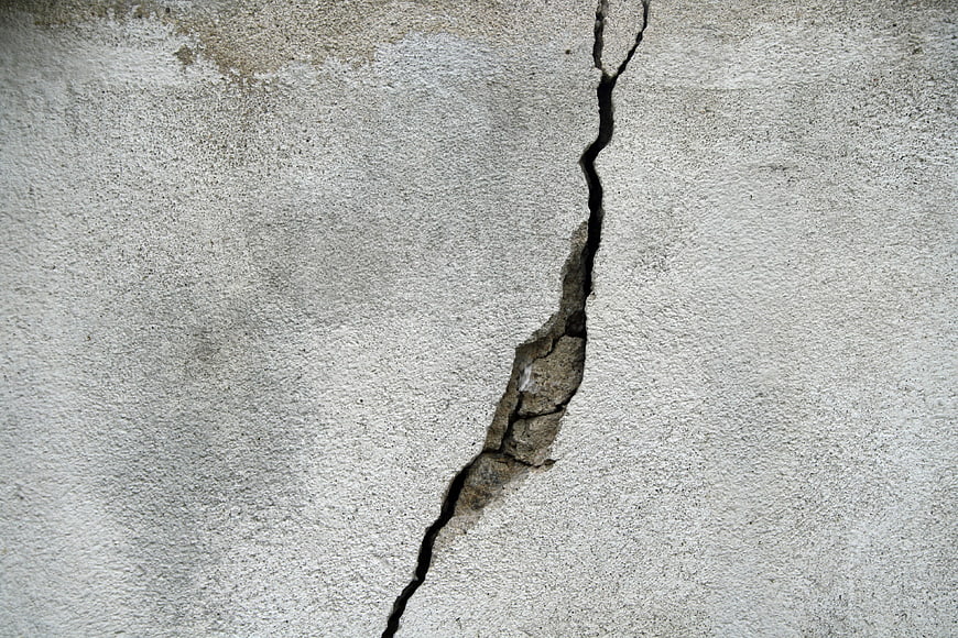 Vertical crack in weathered concrete wall texture