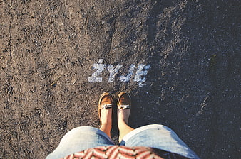 First-person view of feet standing on asphalt with word ZYJE