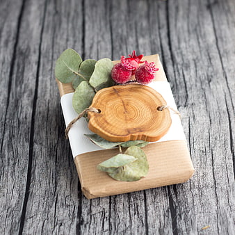 Rustic kraft paper gift box with eucalyptus and red berries on weathered wood