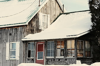 Old weathered wooden house covered in snow