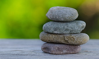 Stacked Zen Stones on Wooden Surface with Green Background