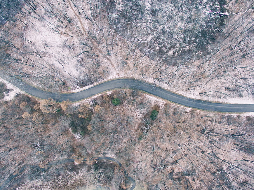 Aerial View of Winding Road Through Winter Forest