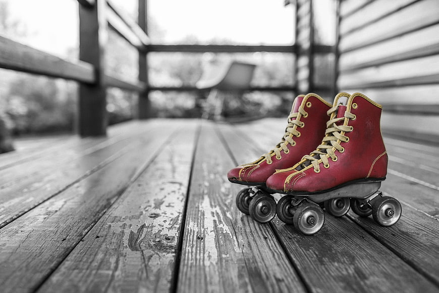 Vintage Red Roller Skates on Wooden Deck