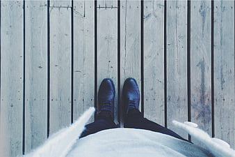 First-person view of black shoes on wooden deck