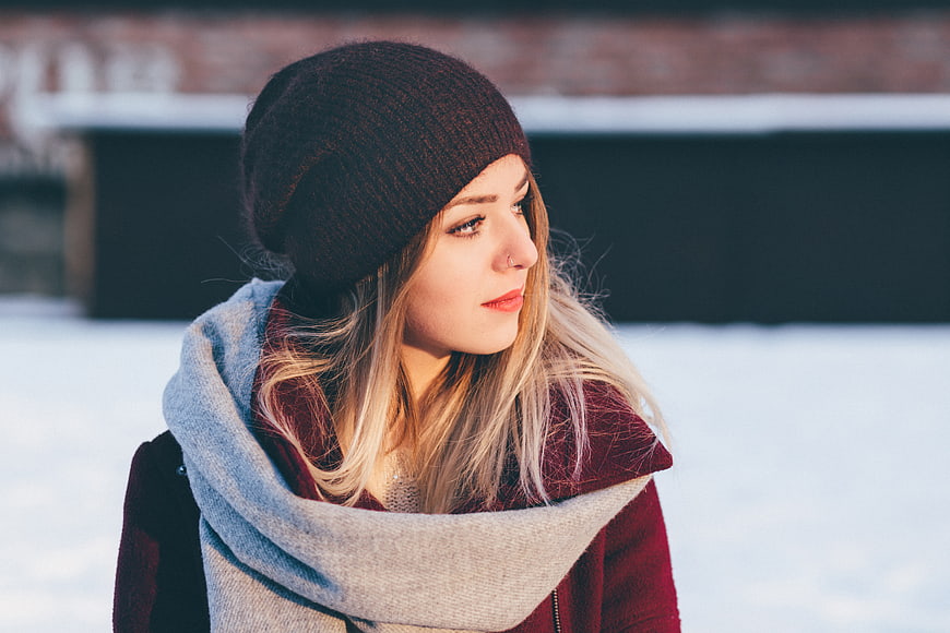 Young Woman in Winter Scarf and Beanie in Snow