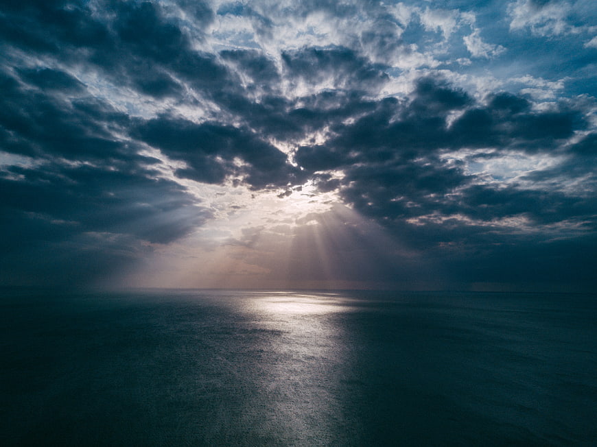 Dramatic Sun Rays Breaking Through Clouds Over Ocean