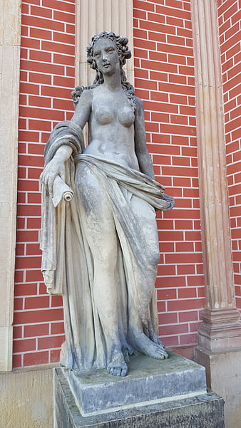 Classical Stone Statue of Woman Against Red Brick Wall