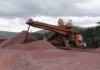 Industrial iron ore mining site with conveyor belt and material piles