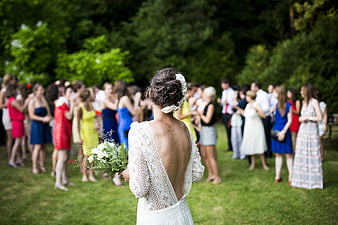 Bride from behind holding bouquet at outdoor wedding ceremony