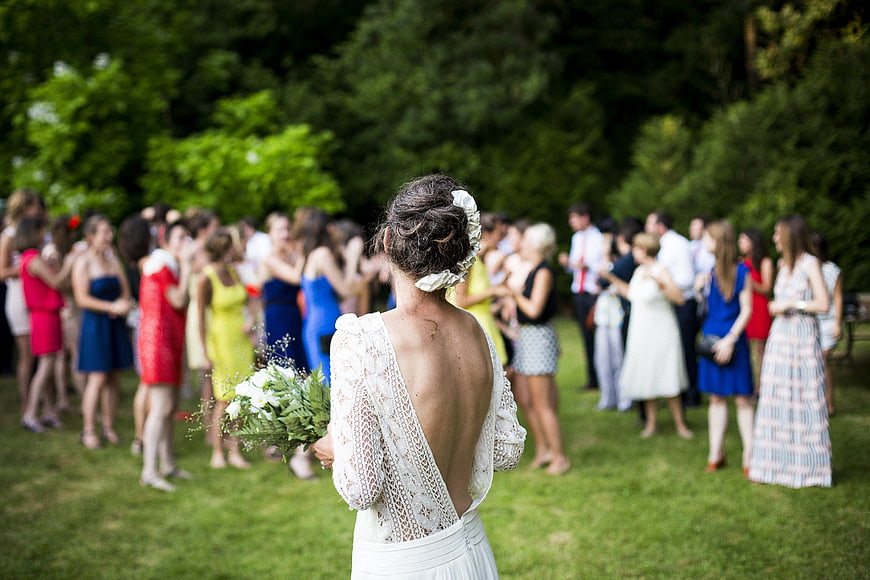 Bride from behind holding bouquet at outdoor wedding ceremony