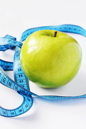 Green Apple with Blue Measuring Tape on White Background