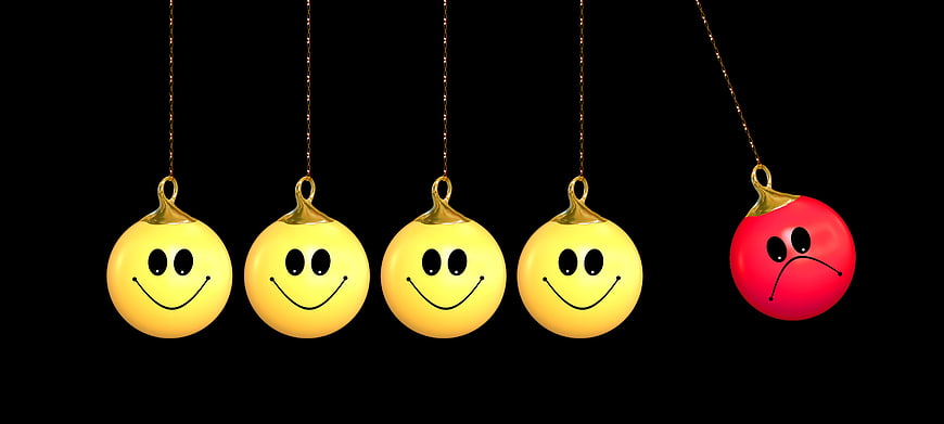 Red angry ornament among yellow smiley faces on black background