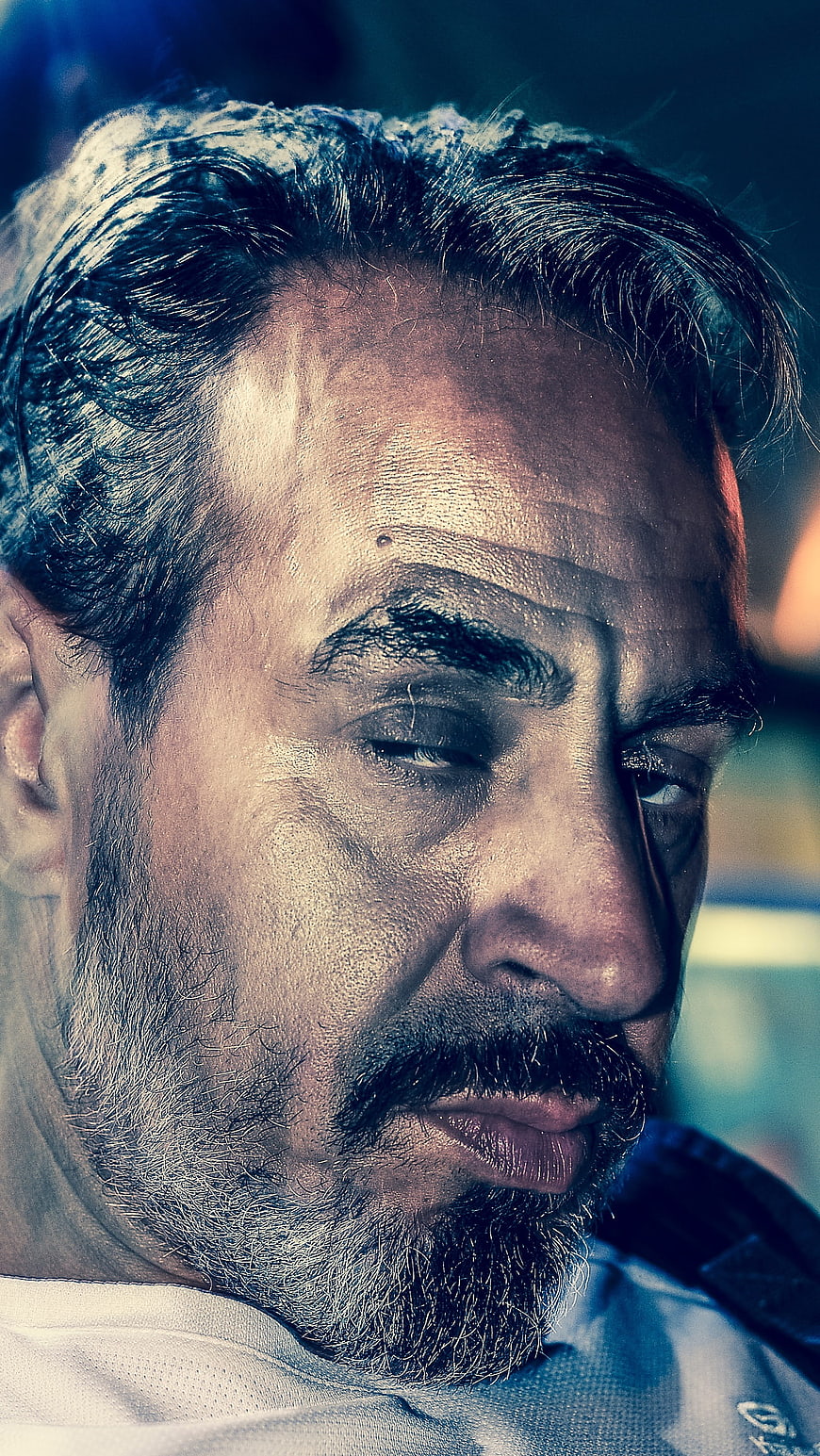 Close-up portrait of a mature man with a beard looking down