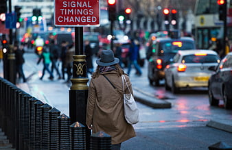 Woman in Coat and Hat Waiting at Busy City Street Crossing