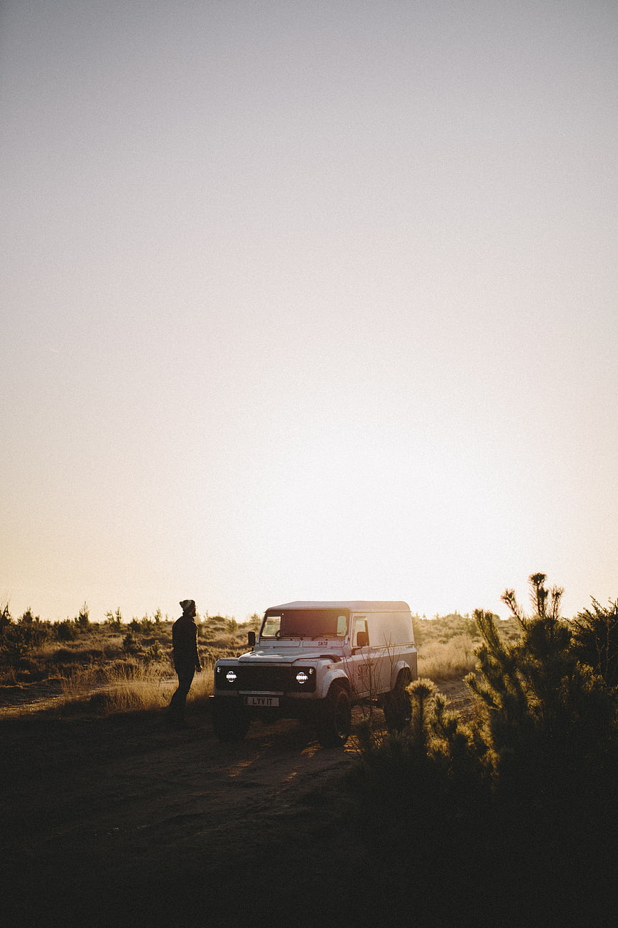 Man standing next to white off-road vehicle in desert landscape