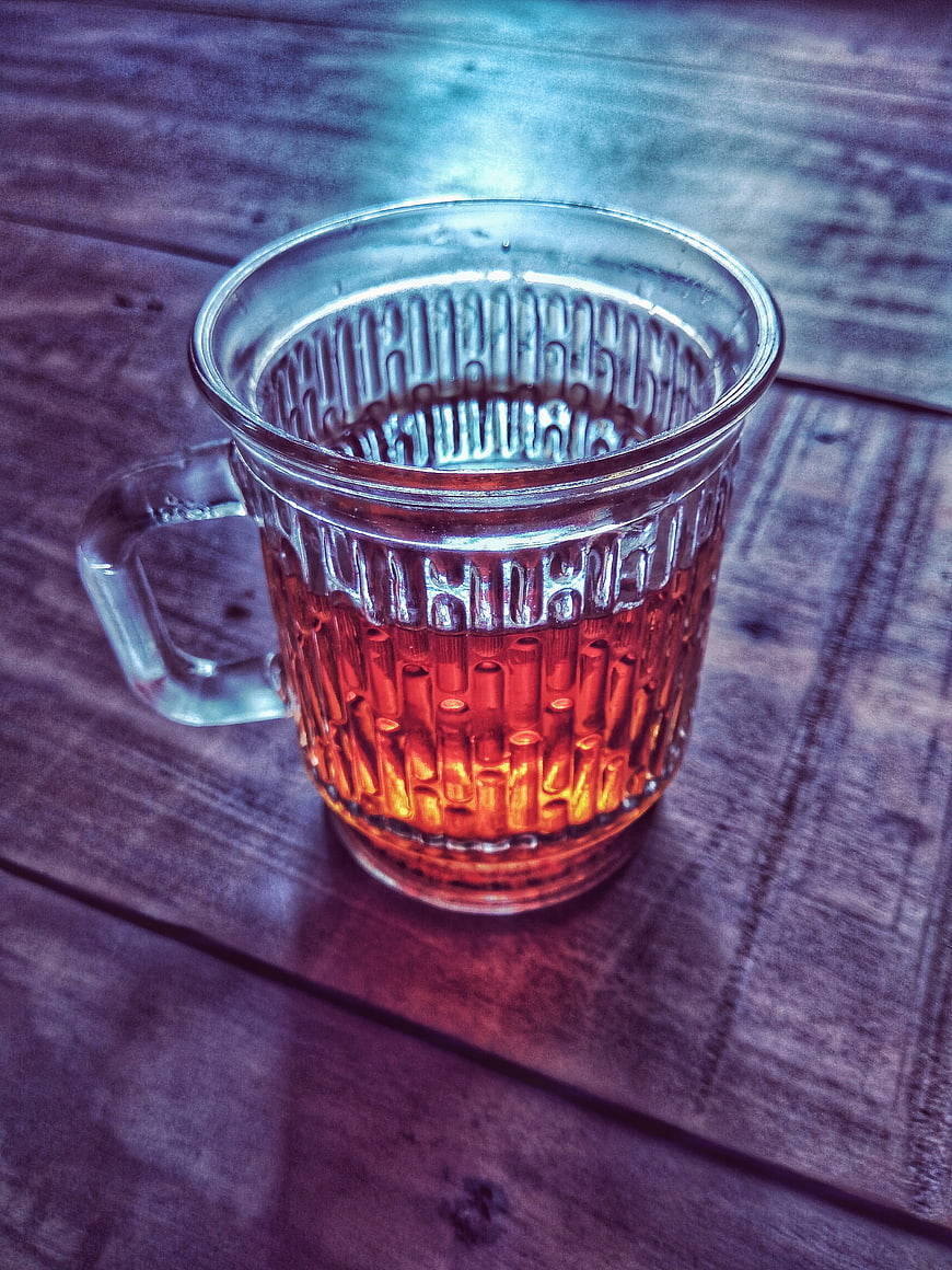 Glass mug of amber tea on rustic wooden table