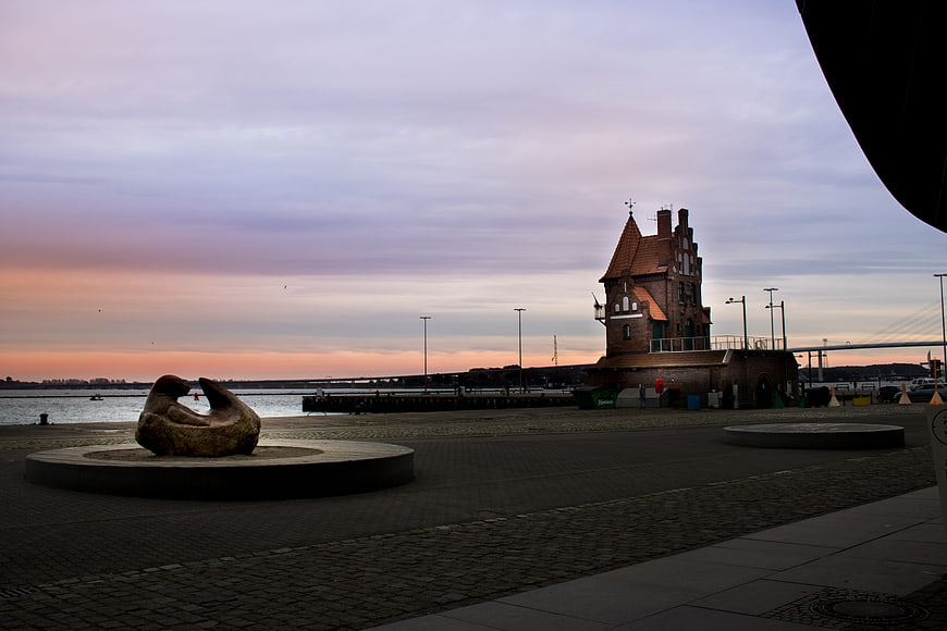 Sunset at Warnemünde with historic tower and sculpture