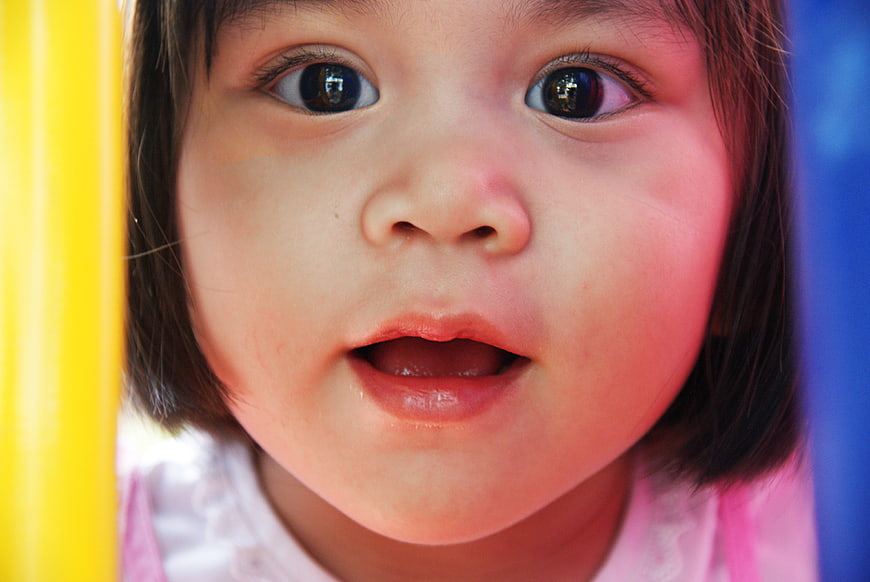 Close-up portrait of cute toddler girl with surprised expression