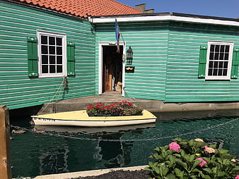 Green floating house with flower boat in canal