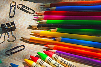 Colorful Pencils and Crayons on Wooden Desk with Paper Clips