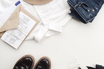 Flat lay of white shirt, jeans, shoes, and travel accessories