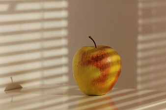 Red and yellow apple with window blinds shadows