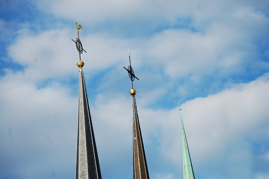 Three church spires against blue sky with clouds