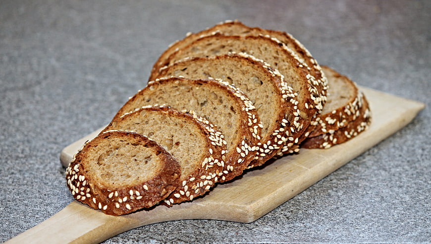 Sliced Whole Grain Rye Bread with Sesame Seeds on Wooden Board