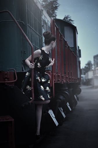 Woman in floral dress climbing vintage train car