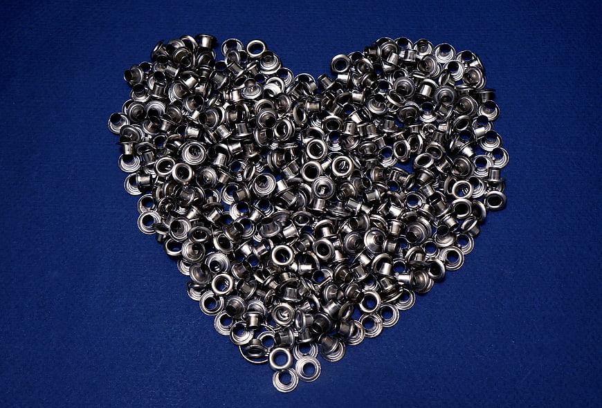 Metal Grommets Arranged in Heart Shape on Blue Background