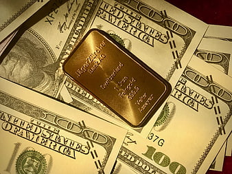 Gold bar on scattered hundred dollar bills