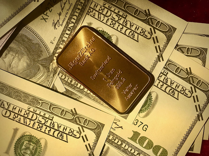 Gold bar on scattered hundred dollar bills