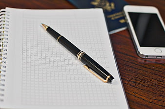 Black pen on notebook with passport and smartphone
