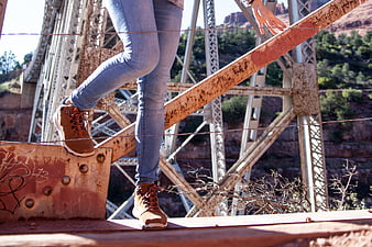 Woman climbing rusty steel bridge structure in desert